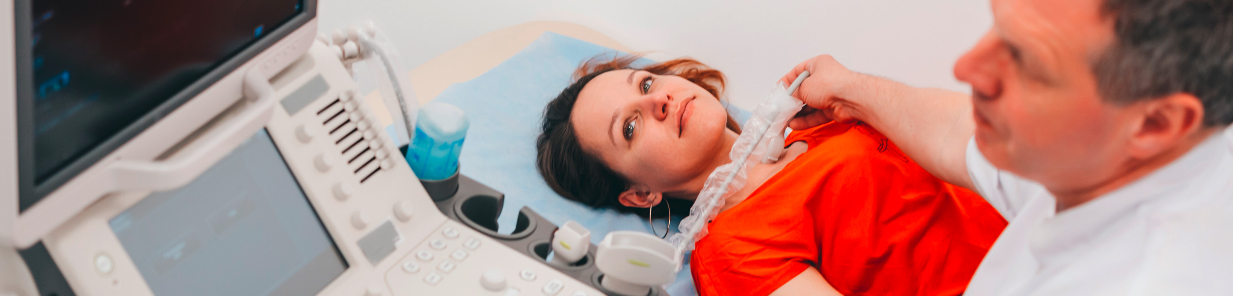 Eine Patientin wird um den Halsbereich mit einem Ultraschallgerät untersucht.